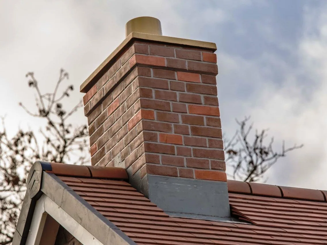 Brick chimney and clay pot on a UK pitched tiled roof