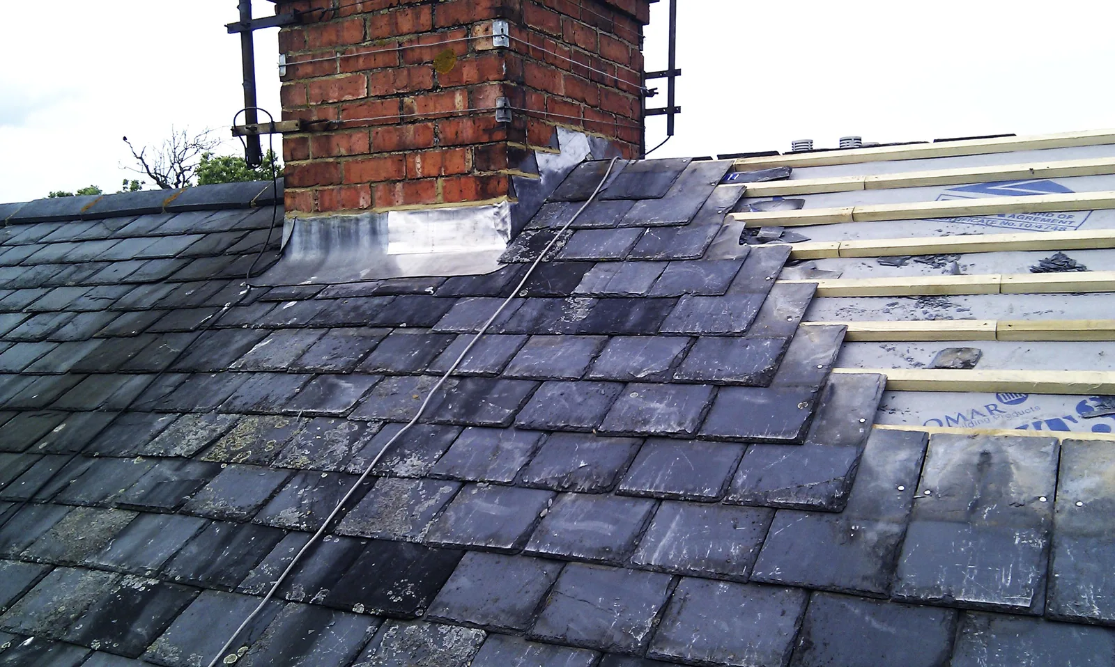 New slate roof covering being laid on a British property