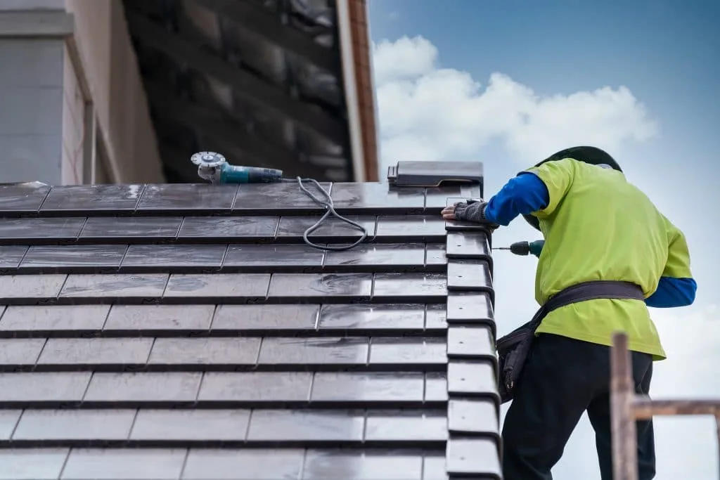 Roofer laying new slates on a UK house roof
