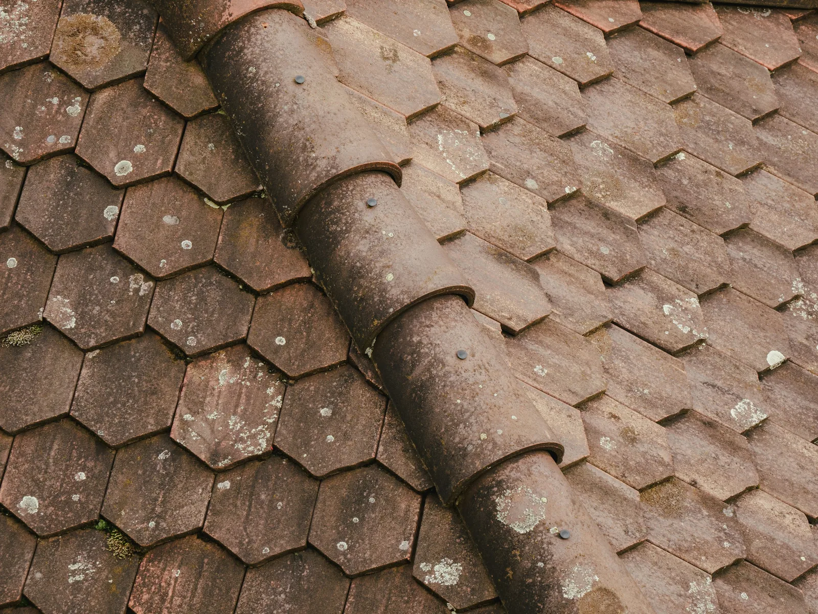 Weathered clay roof tiles in need of repair on a UK property