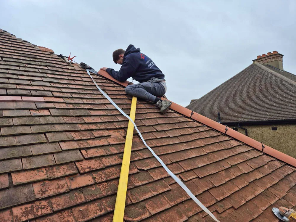 Roofer carrying out repairs on a British tiled roof